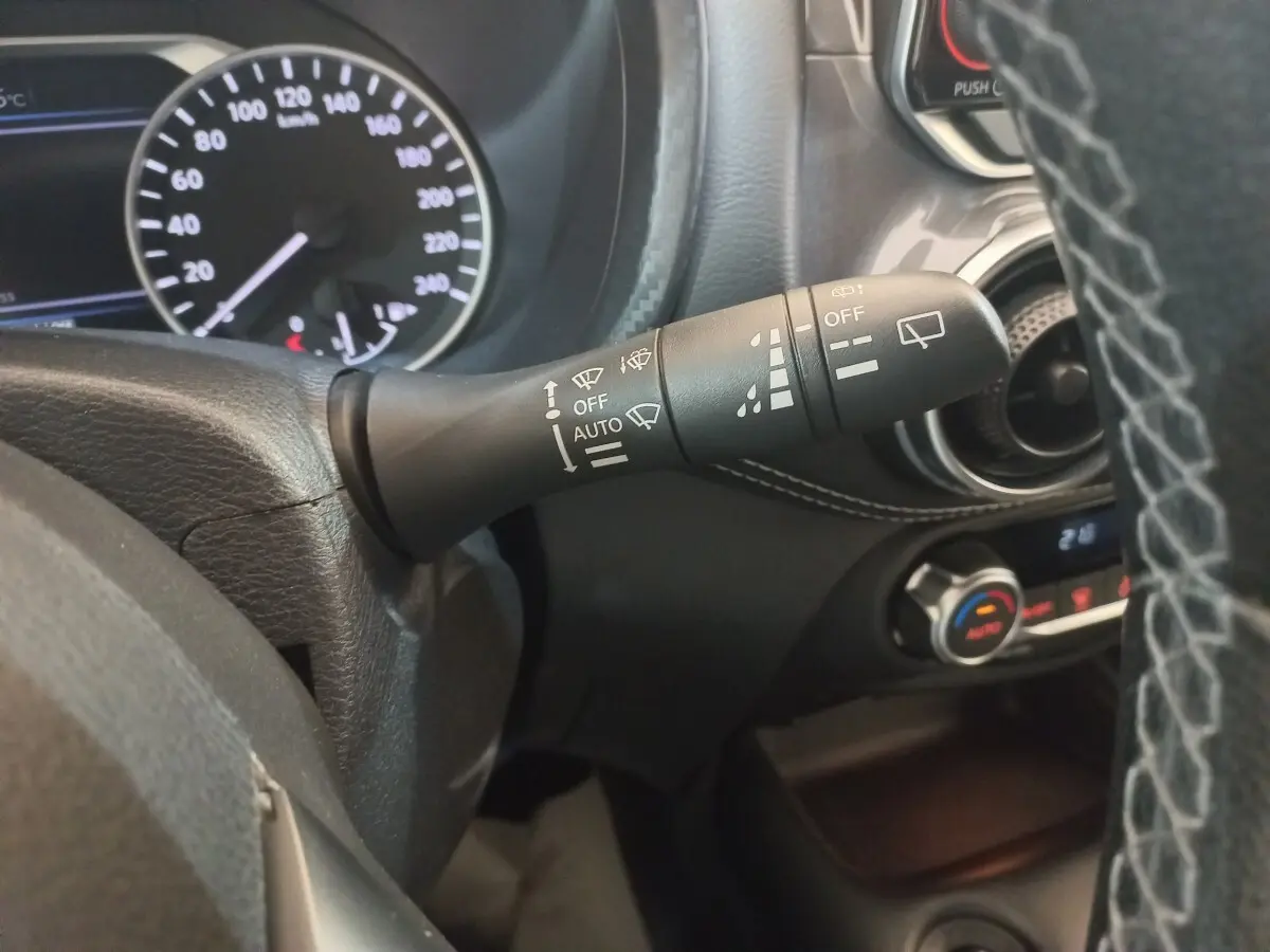 Gros plan sur la manette d’essuie-glace du tableau de bord du Nissan Juke Hybrid 143 Business+ gris foncé, intérieur noir.