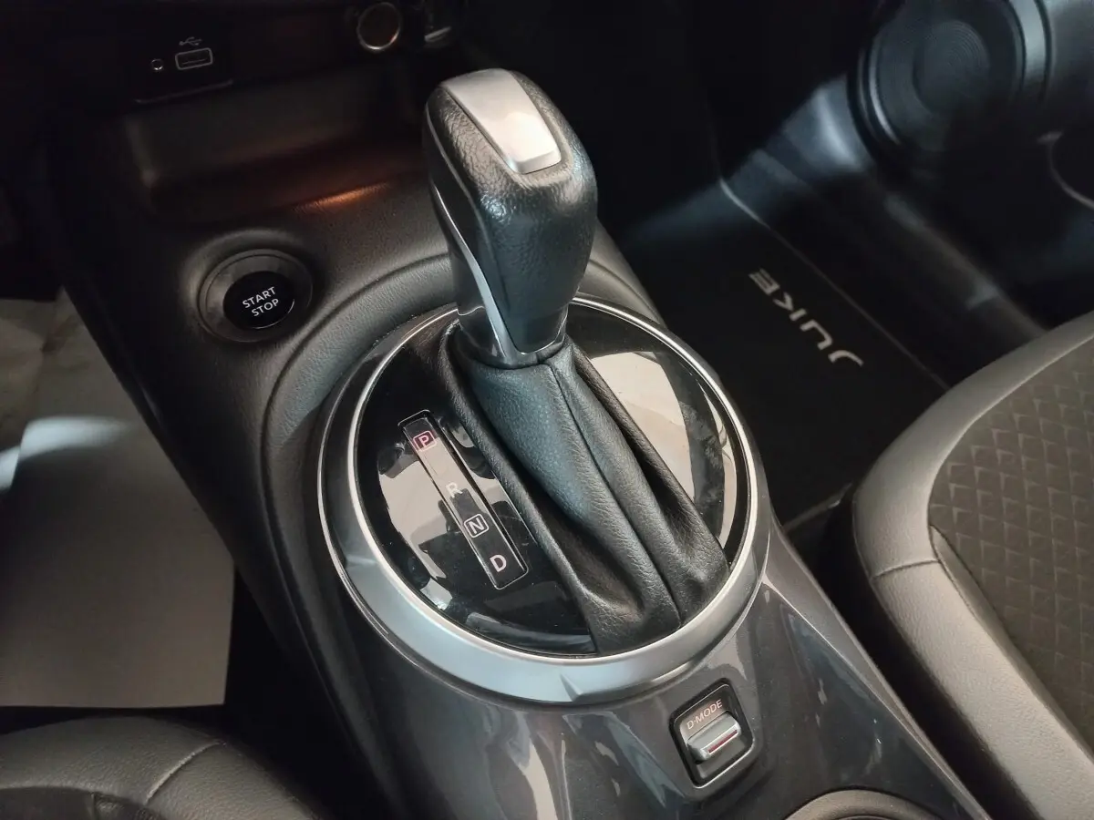 Gros plan sur la commande de boîte automatique et bouton start/stop dans l’habitacle gris foncé du Nissan Juke Hybrid 2023.