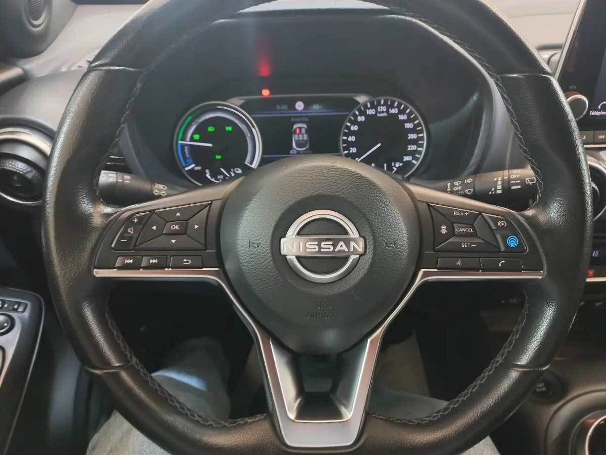 Vue rapprochée du volant cuir et alu multifonctions du Nissan Juke Hybrid 143 Business+ 2023 avec tableau de bord numérique.