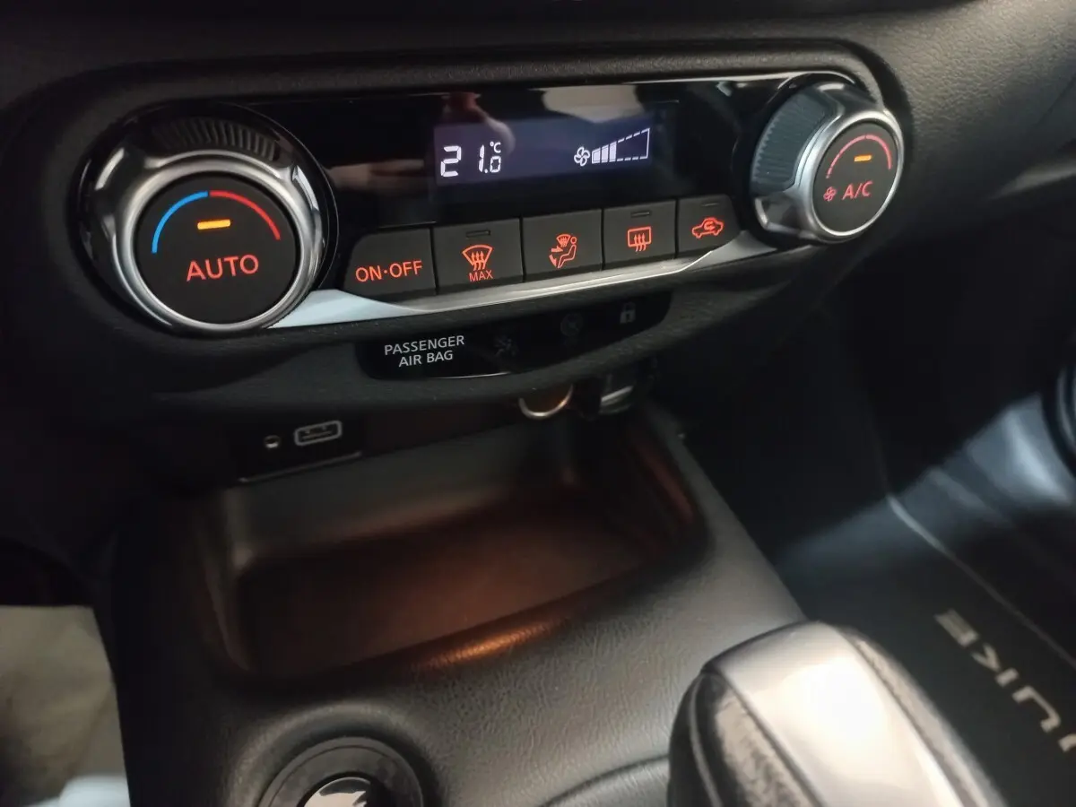 Gros plan sur la console centrale du Nissan Juke Hybrid 143 Business+ 2023, avec commandes climatisation et affichage digital.