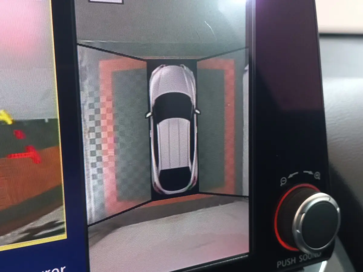 Vue écran intérieur montrant la caméra 360° du Nissan Juke Hybrid 143 Business+ gris foncé en vue aérienne.