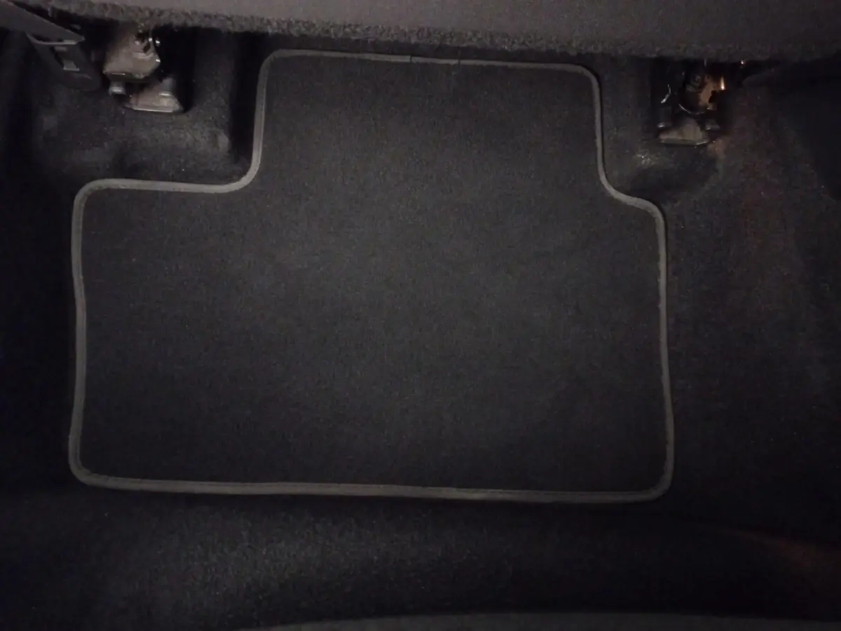 Vue intérieure du coffre du Nissan Juke Hybrid 143 Business+ 2023, tapis de sol gris foncé visible au sol.