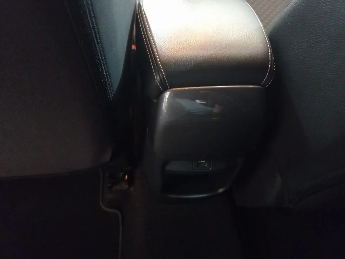 Vue rapprochée de la console centrale arrière en cuir noir avec port USB du Nissan Juke Hybrid 2023 gris foncé.