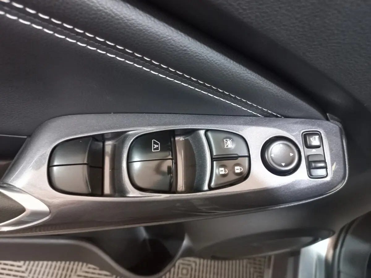 Gros plan sur les commandes de lève-vitres et rétroviseurs côté conducteur du Nissan Juke Hybrid 143 Business+ gris foncé.