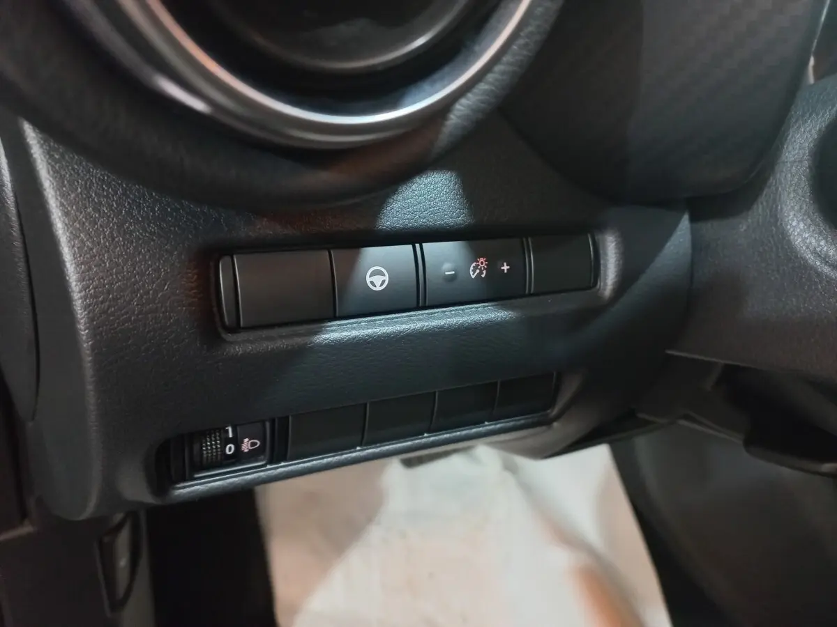 Détail intérieur du tableau de bord du Nissan Juke Hybrid 143 Business+ 2023, montrant les commandes de réglage du volant.