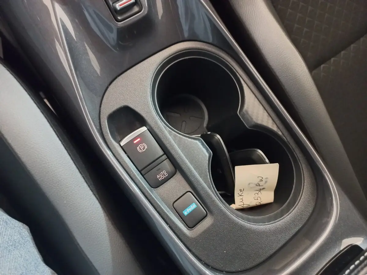 Gros plan intérieur sur la console centrale noire du Nissan Juke Hybrid 143 Business+ avec boutons e-Pedal et frein à main électrique.
