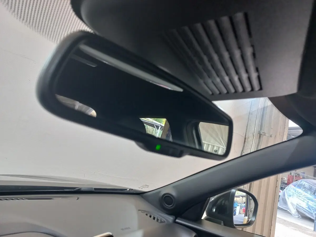 Intérieur du Nissan Juke Hybrid 143 Business+ 2023, vue du rétroviseur intérieur et du côté droit gris foncé visible à l'extérieur.