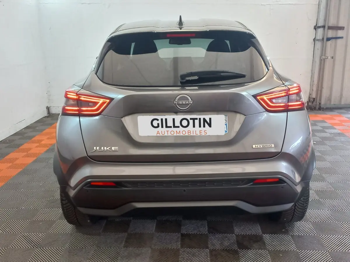 Vue arrière d'un Nissan Juke Hybrid gris foncé avec feux LED allumés dans un garage fermé.