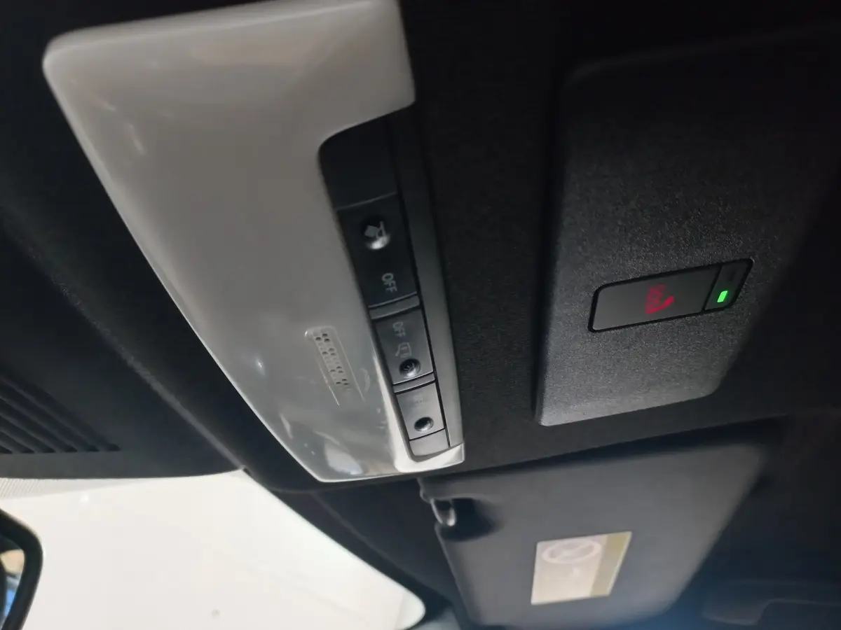 Vue intérieure du plafond avec commandes d'éclairage et bouton SOS du Nissan Juke Hybrid 143 Business+ gris foncé 2023.