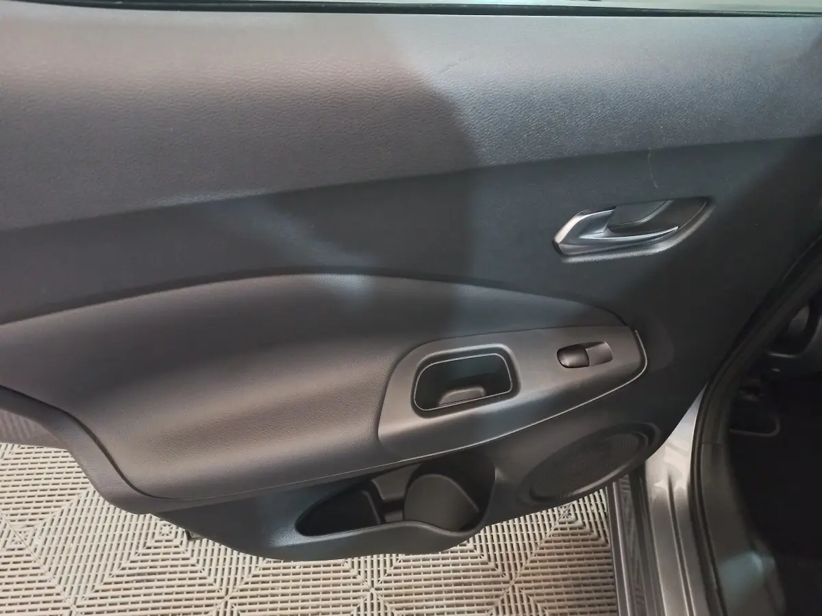 Vue rapprochée de la porte avant droite intérieure du Nissan Juke Hybrid 143 Business+ gris foncé, avec poignée et commande de vitre.