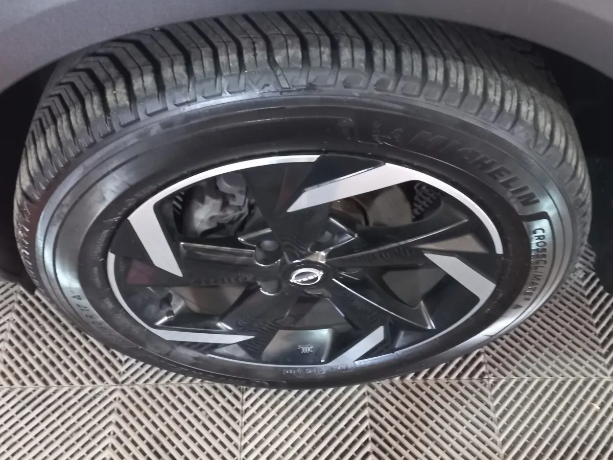 Gros plan sur la roue avant droite du Nissan Juke Hybrid 143 Business+ avec jante noire et inserts argentés.