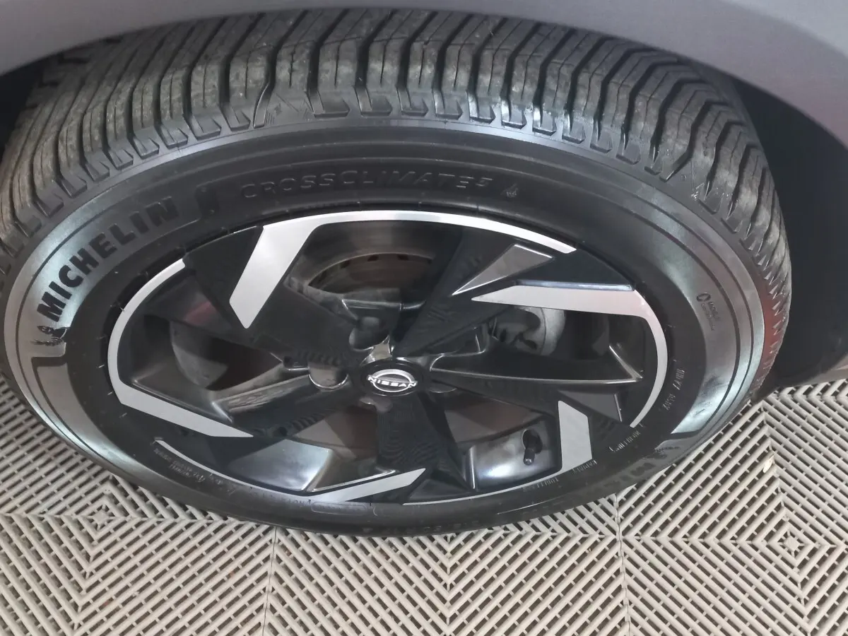 Gros plan sur la roue avant droite du Nissan Juke Hybrid 143 Business+ gris foncé avec jante noire et argentée.