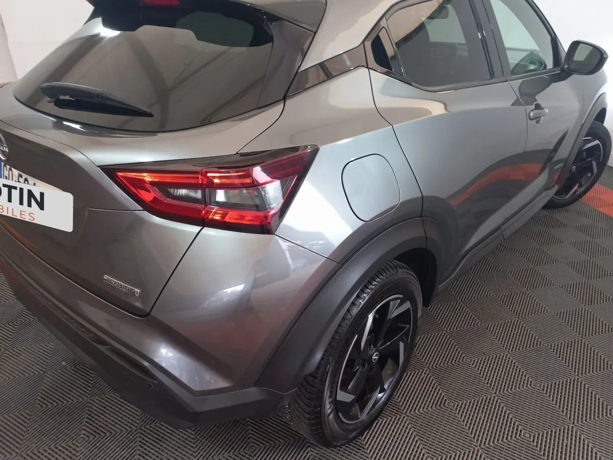 Vue 3/4 arrière droit du Nissan Juke Hybrid 143 Business+ gris foncé avec jantes noires et feux LED distinctifs.