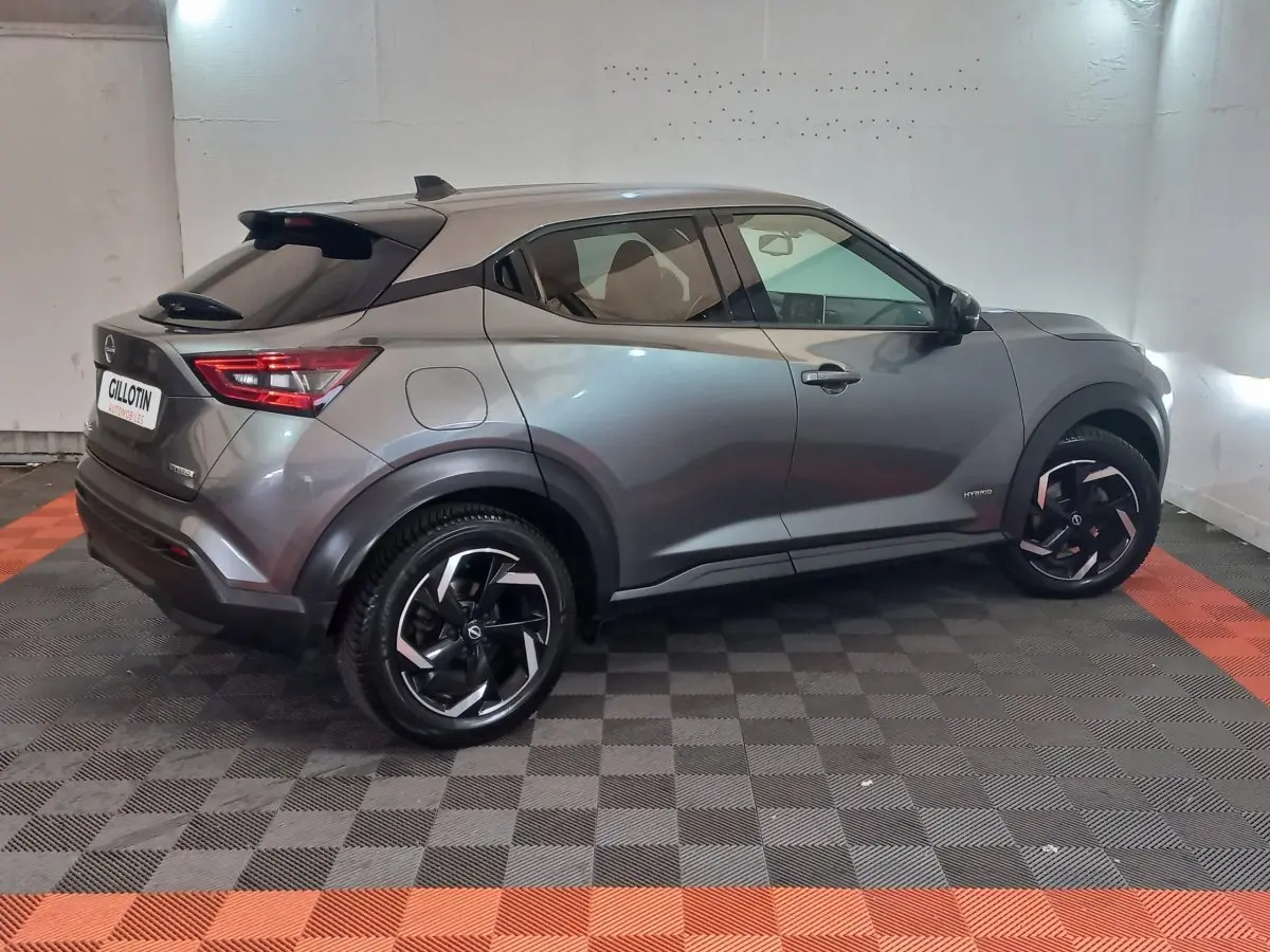 Nissan Juke Hybrid gris foncé vu de profil côté droit, avec jantes noires et détails modernes au niveau des ailes.