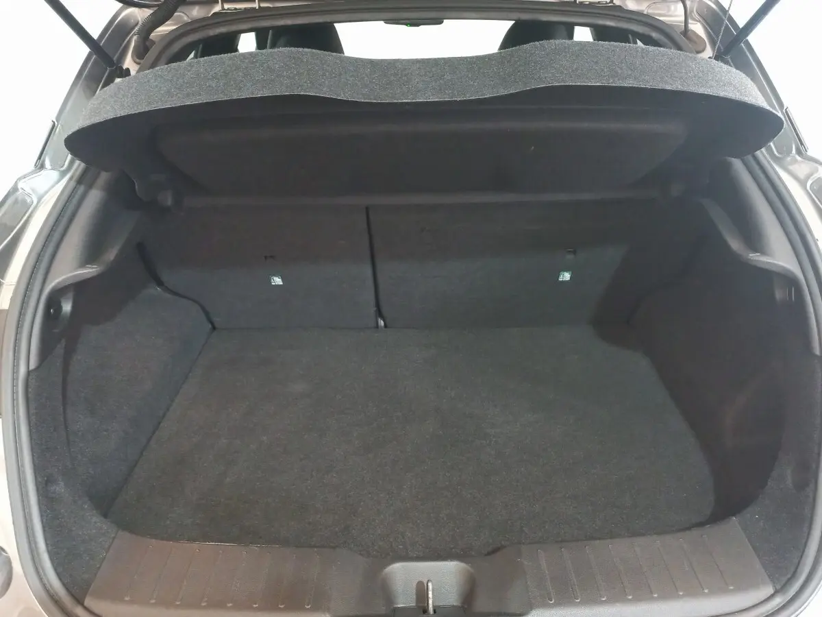 Coffre ouvert du Nissan Juke Hybrid 143 Business+ gris foncé, vue arrière montrant l’espace de chargement vide.