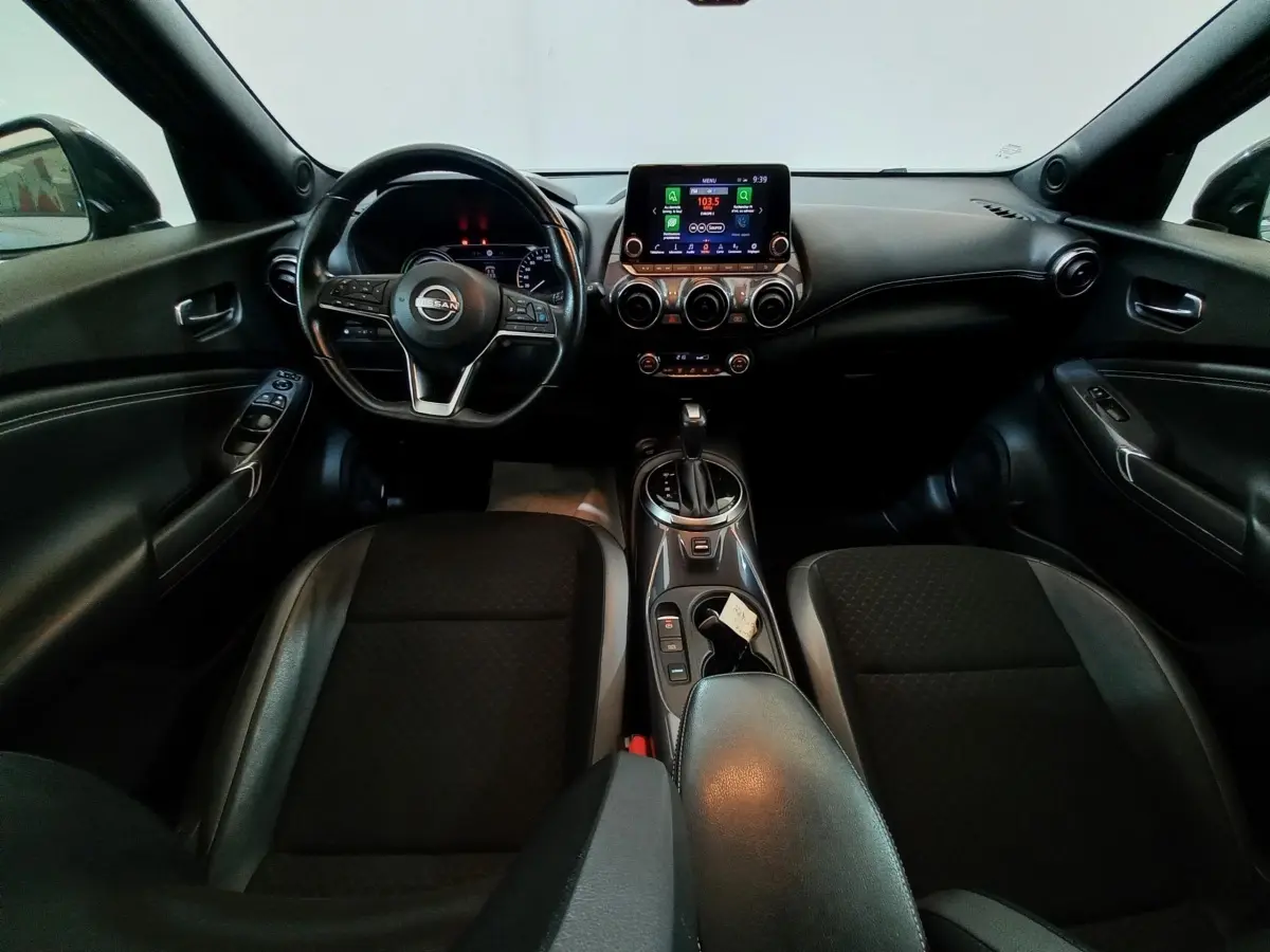 Vue intérieure avant du Nissan Juke Hybrid 143 Business+ 2023, tableau de bord et volant cuir alu noir, console centrale avec écran tactile.