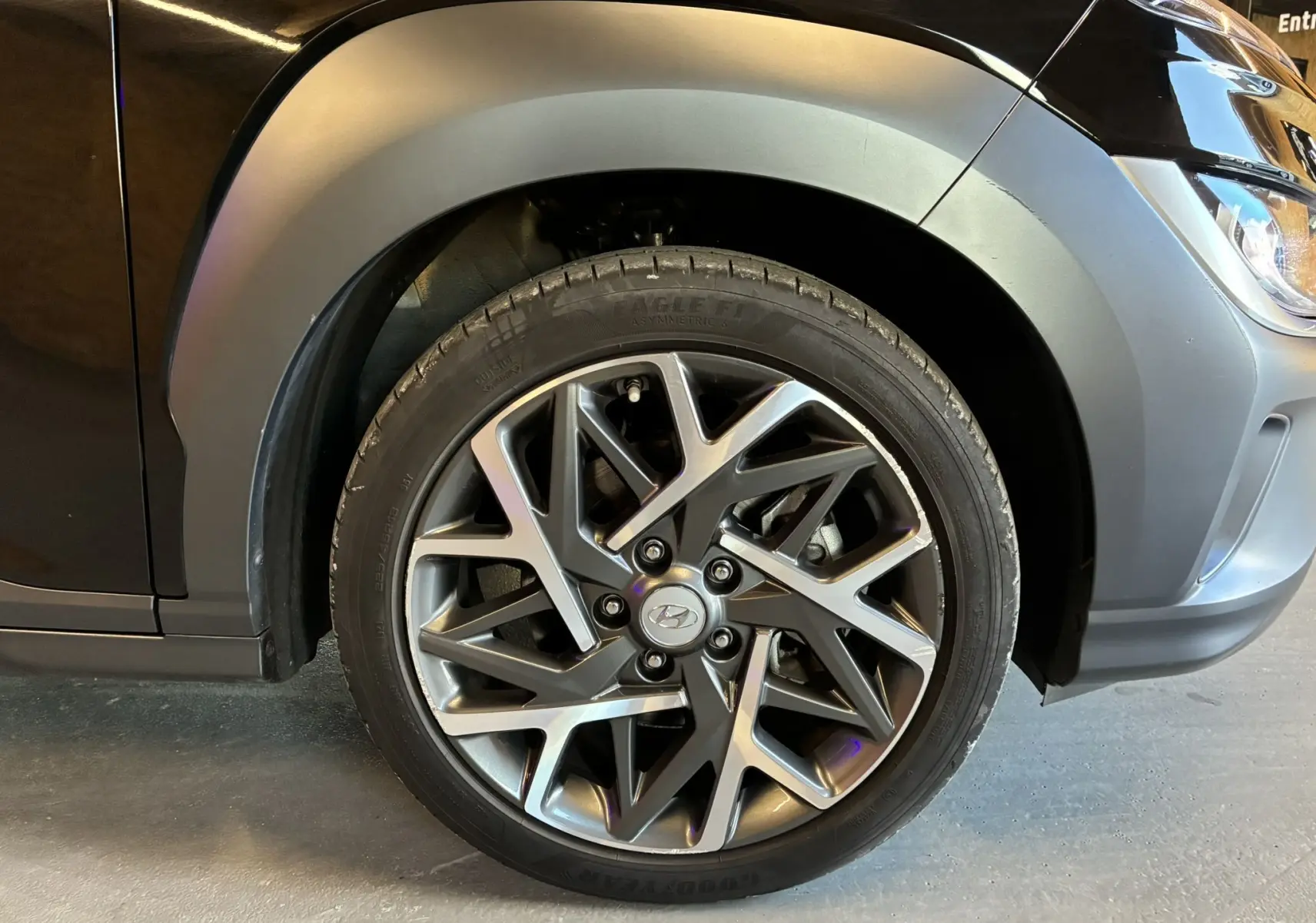 Gros plan sur la roue avant gauche noire d'un Hyundai Kona 2023, mettant en valeur la jante alliage au design moderne.