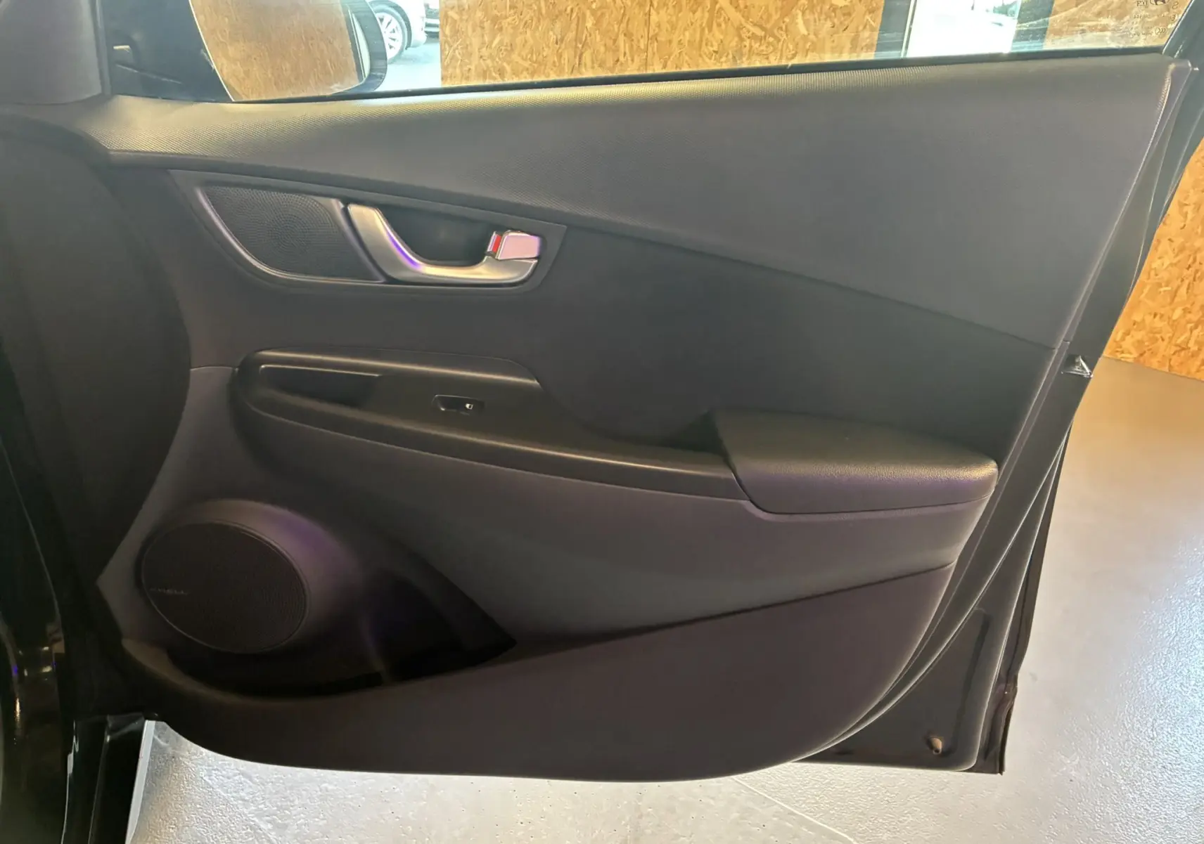 Panneau intérieur noir de la porte arrière droite du Hyundai Kona 2023, avec poignée argentée et haut-parleur intégré.