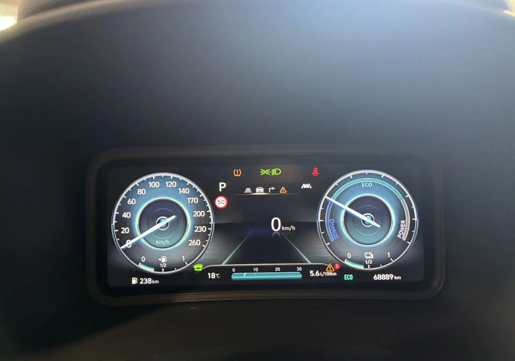 Tableau de bord numérique du Hyundai Kona 2023 affichant la vitesse à 0 km/h et indicateurs hybrides en bleu et blanc.