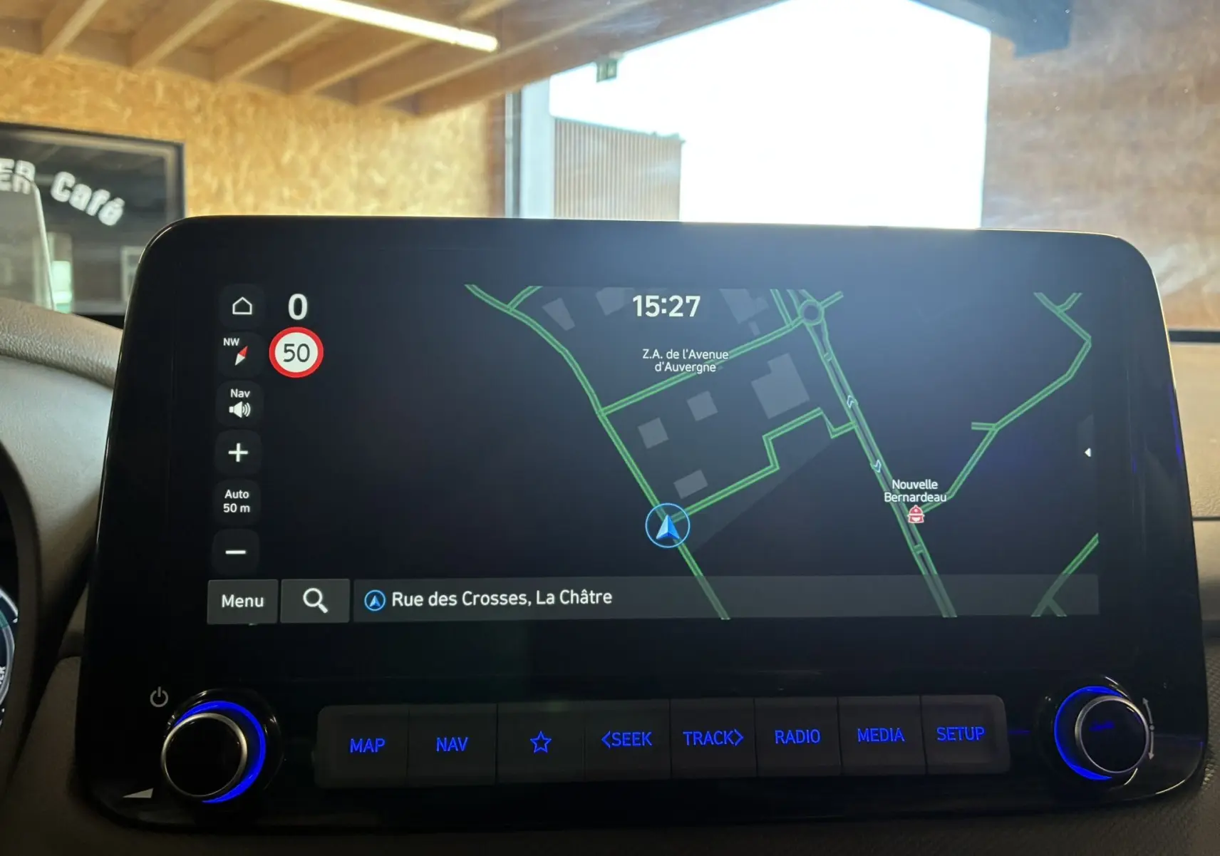 Écran tactile du système de navigation du Hyundai Kona 2023 affichant une carte et commandes rétroéclairées bleues.