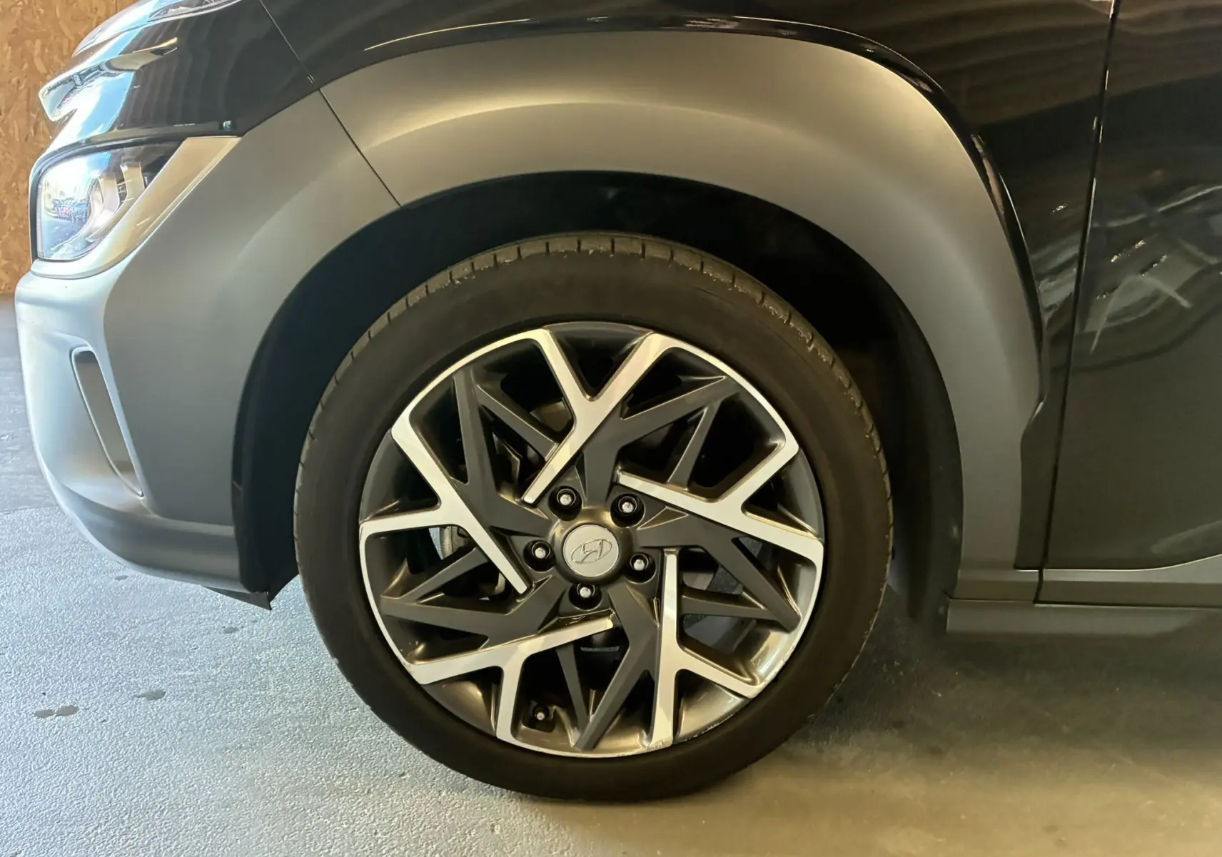 Gros plan sur la roue avant gauche du Hyundai Kona noir 2023, mettant en valeur la jante alliage au design moderne.