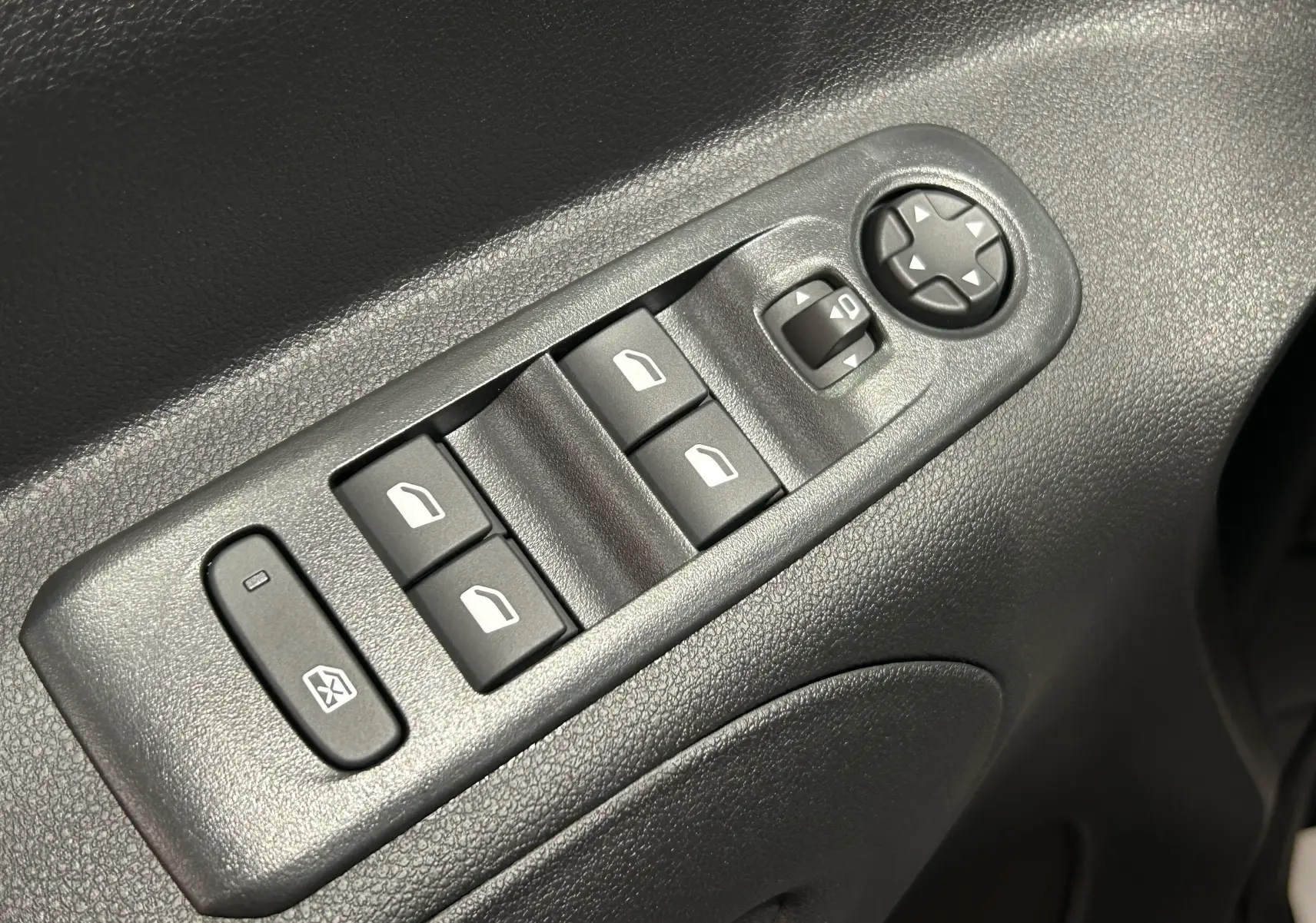 Gros plan sur les commandes électriques des vitres et des rétroviseurs côté conducteur du Citroën Berlingo Multispace gris Artense.