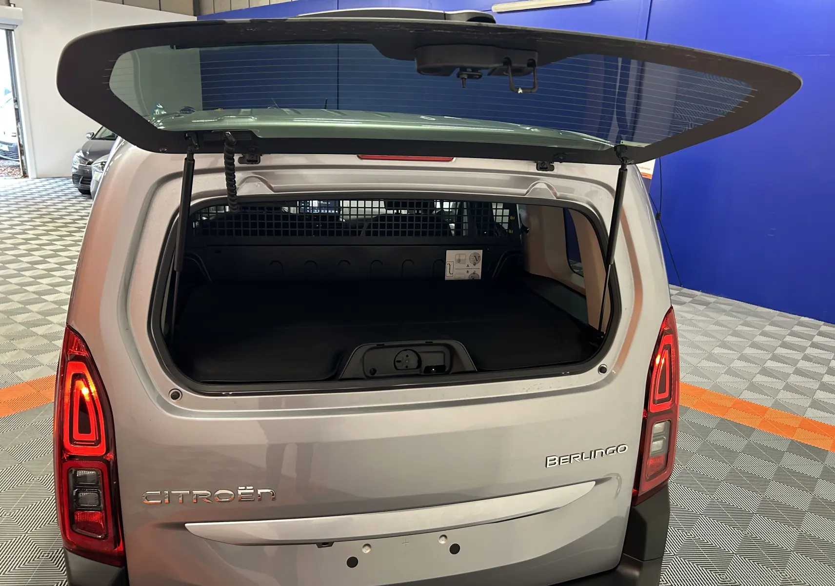 Vue arrière d'un Citroën Berlingo Multispace gris Artense avec hayon ouvert dans un showroom.