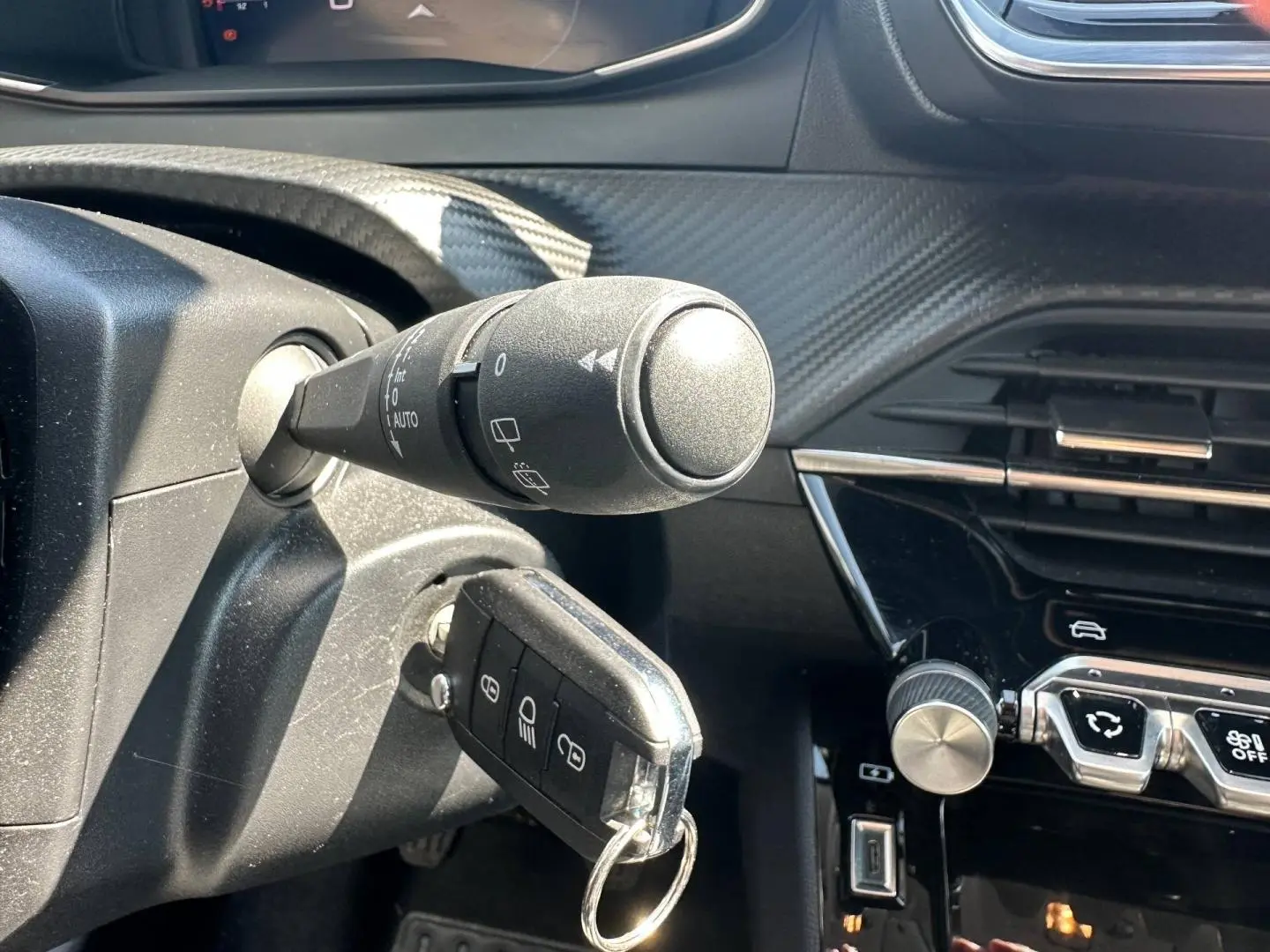 Gros plan intérieur sur la colonne de direction et la clé insérée d'une Peugeot 208 gris Selenium, avec tableau de bord noir brillant.