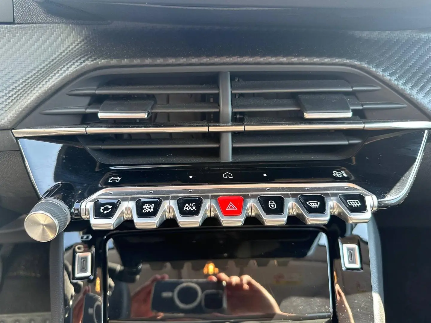Vue rapprochée du tableau de bord de la Peugeot 208 2025, boutons de commande et aérateurs noirs avec finition chrome.
