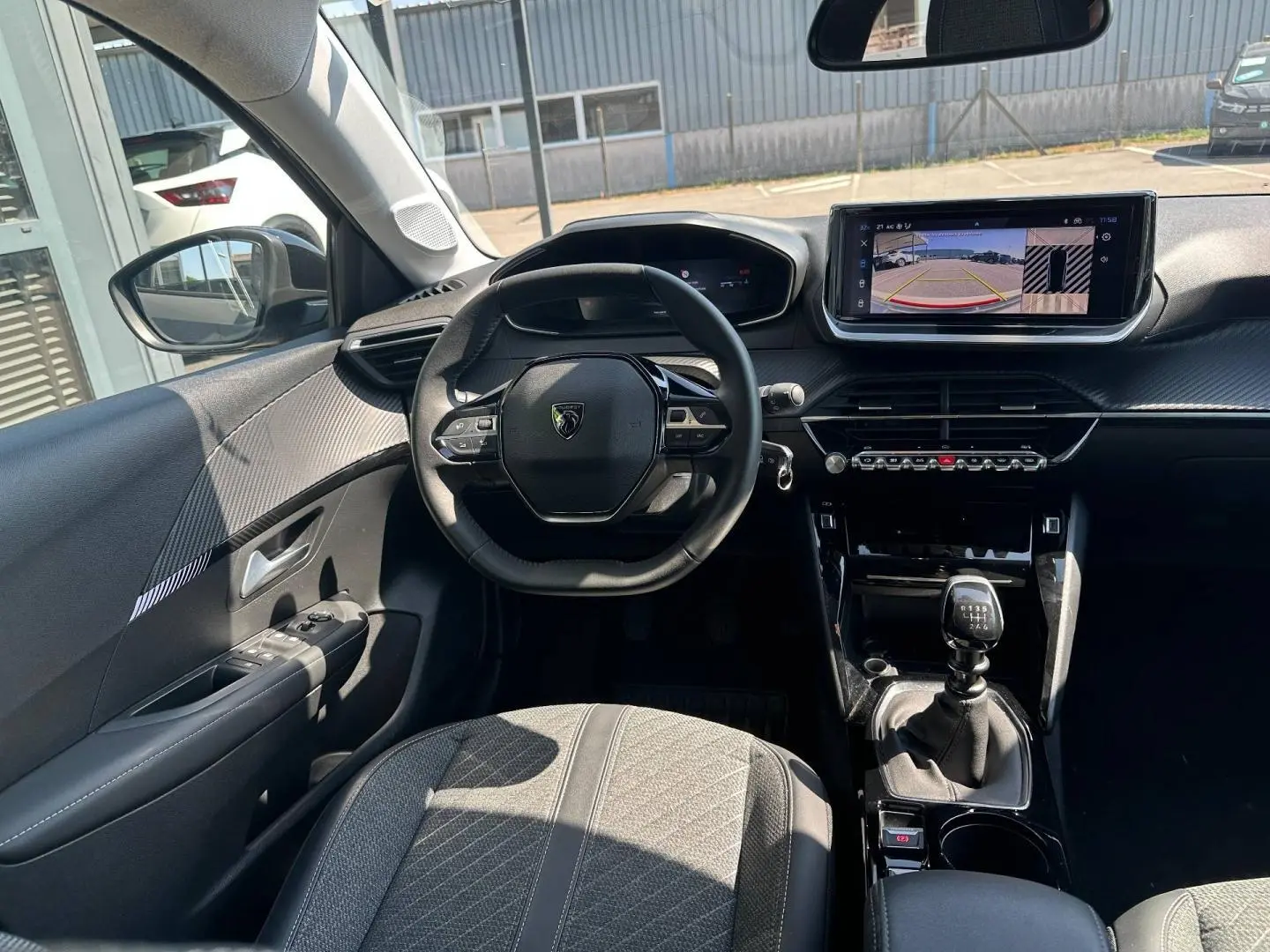 Vue intérieure avant de la Peugeot 208 1.2 100ch S&S Allure avec tableau de bord noir et écran tactile central.