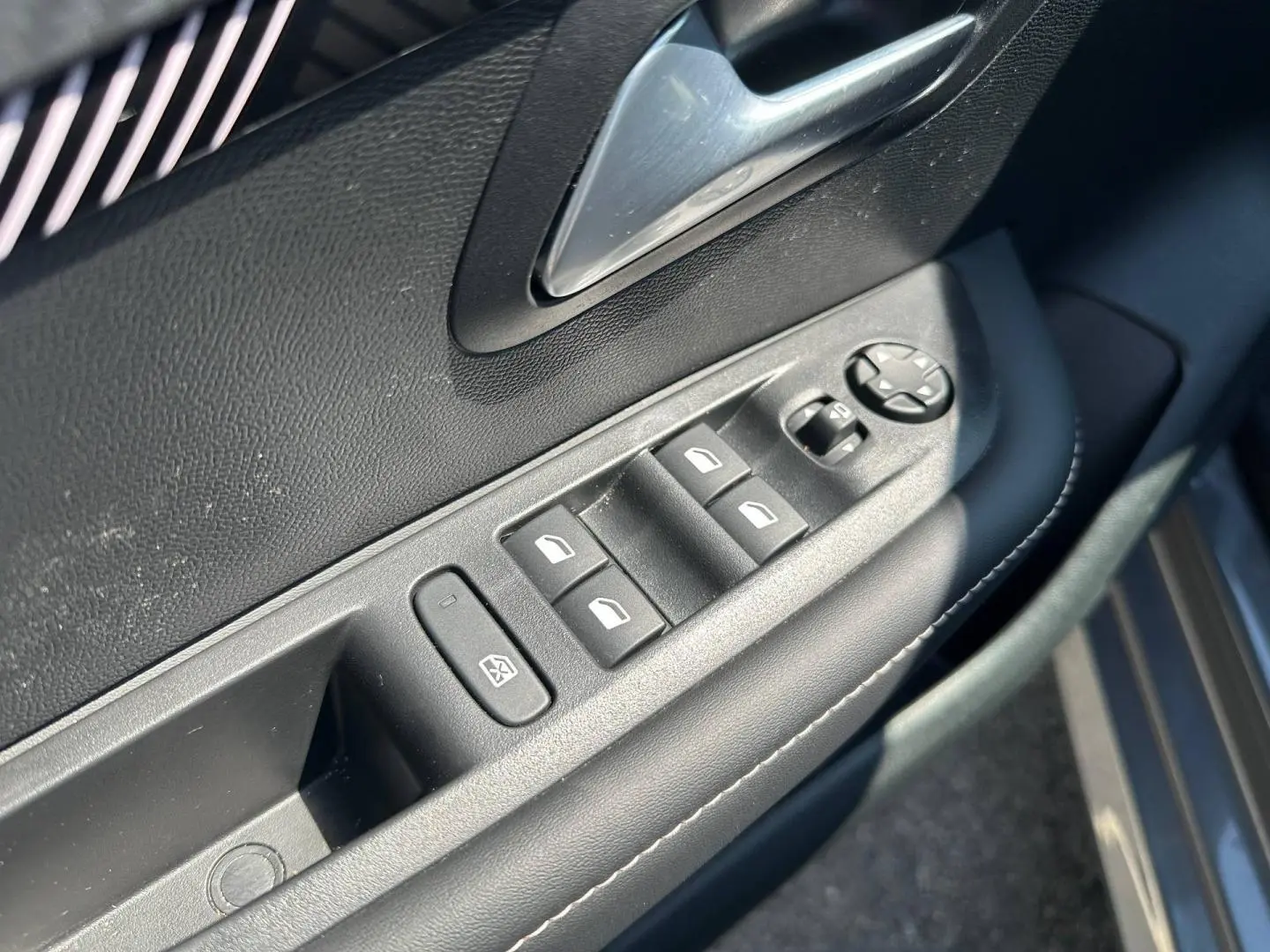 Commande des vitres électriques et rétroviseurs sur la porte côté gauche d'une Peugeot 208 gris Selenium 2025.