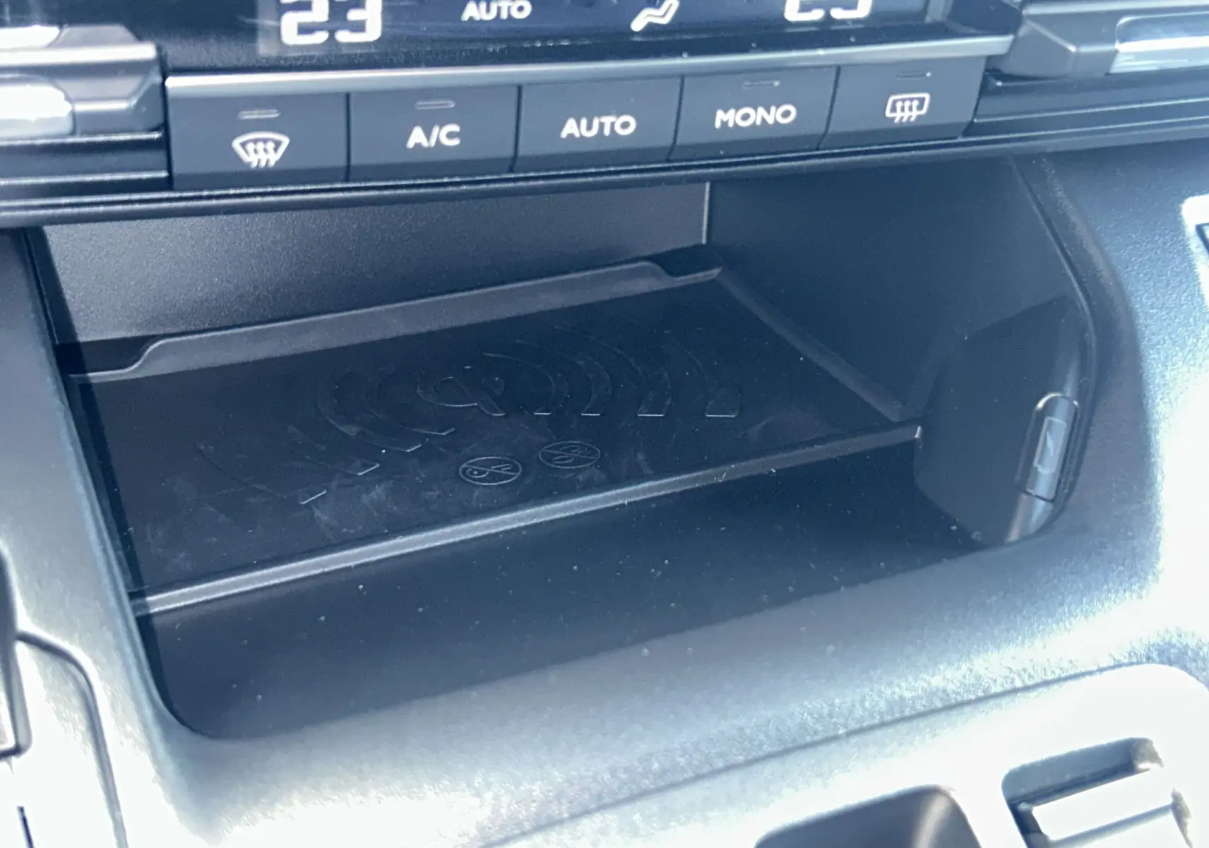 Gros plan sur la console centrale du Citroën Berlingo Multispace 2025, montrant le plateau de recharge sans fil et commandes climatisation.