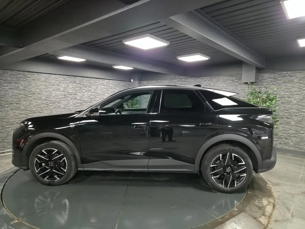 Peugeot 3008 noir en profil droit dans un intérieur, avec jantes alliage noires et détails noirs mats.