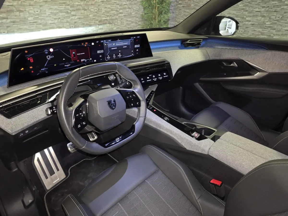 Intérieur du Peugeot 3008 GT 2025 vu côté conducteur, tableau de bord numérique et sellerie gris/noir moderne.