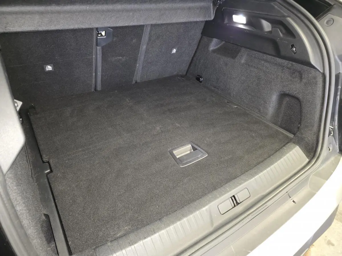 Coffre spacieux et propre du Peugeot 3008 noir, vu de l'arrière avec plancher plat et éclairage LED intégré.