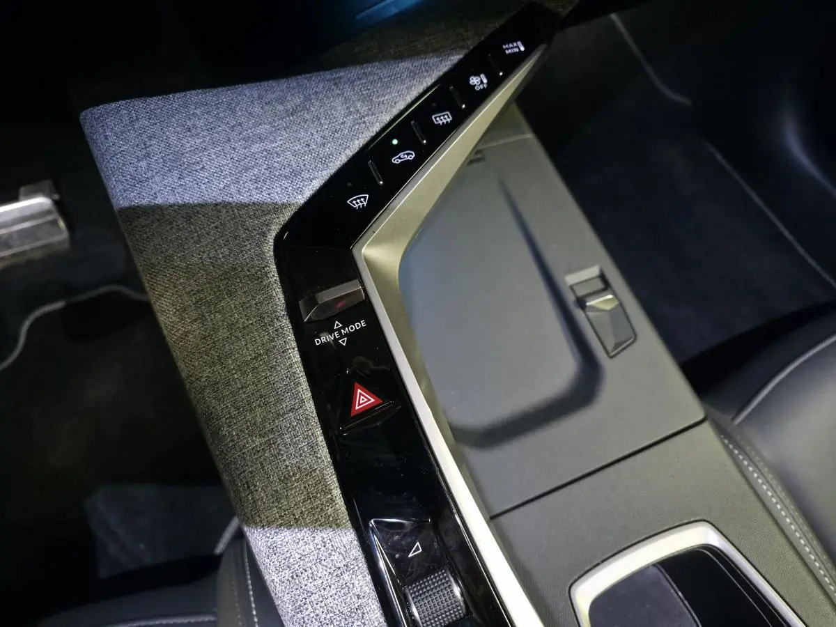 Vue plongeante sur la console centrale du Peugeot 3008 2025, avec tissu gris et commandes noires laquées.