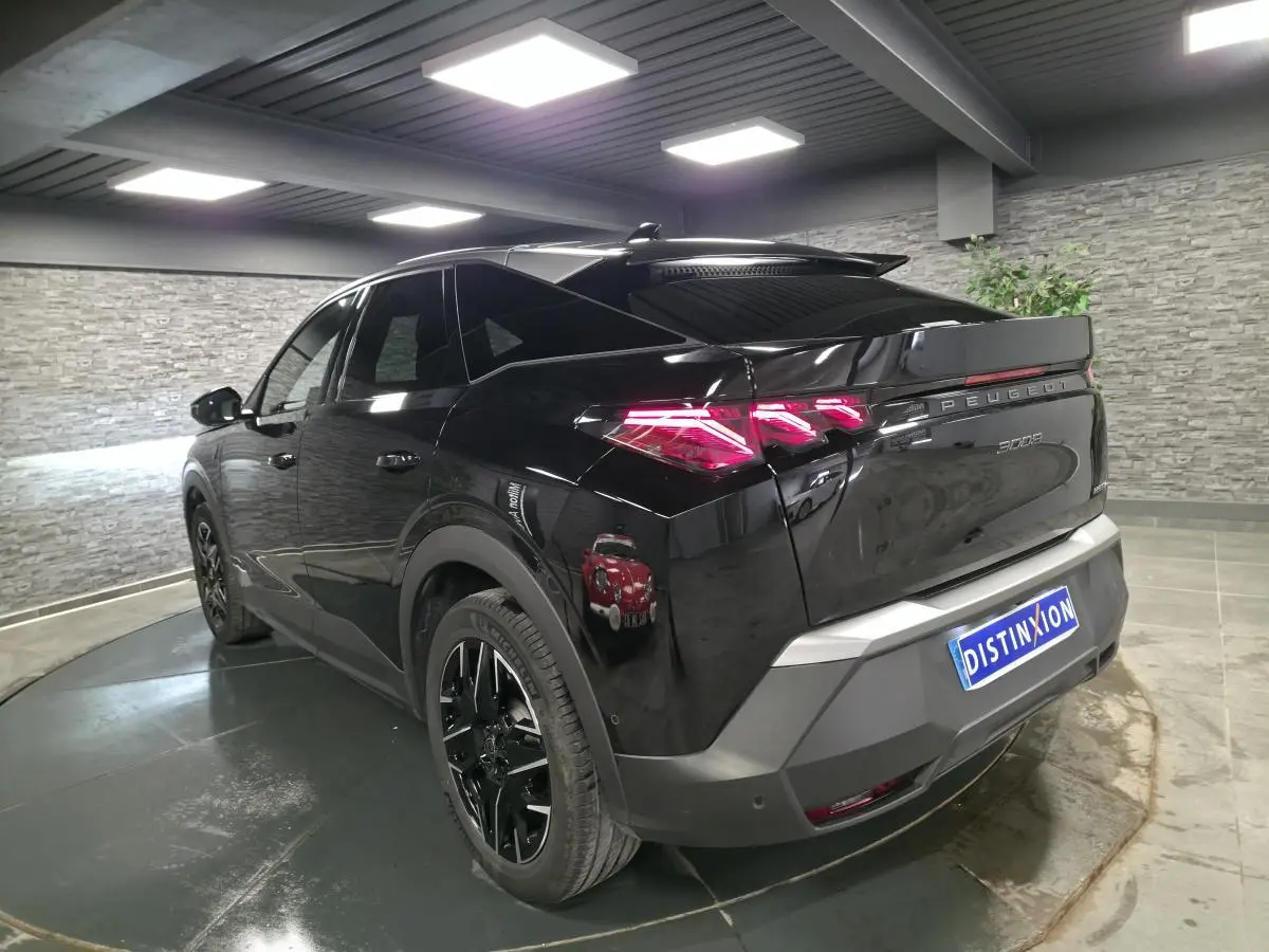 Peugeot 3008 noir vue 3/4 arrière droit en intérieur, feux arrière LED et jantes alliage noires visibles.