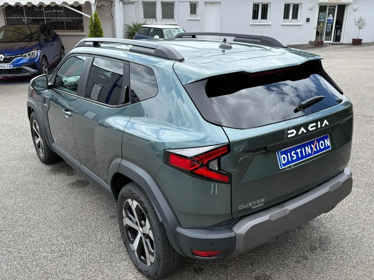 Vue 3/4 arrière droite du Dacia Duster Hybrid 140 Journey vert cèdre avec barres de toit noires et feux arrière LED.