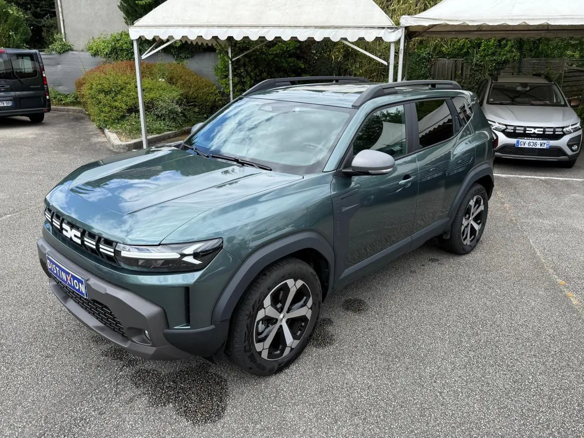 Dacia Duster Hybrid 140 Journey vert cèdre en 3/4 avant droit, avec jantes noires et toit ouvrant visible.