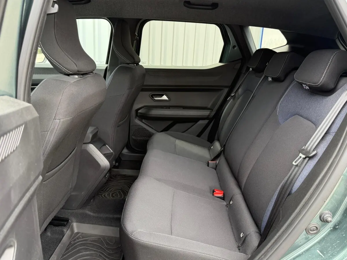 Vue intérieure côté droit sur la banquette arrière noire du Dacia Duster Hybrid 140 Journey vert cèdre 2025.