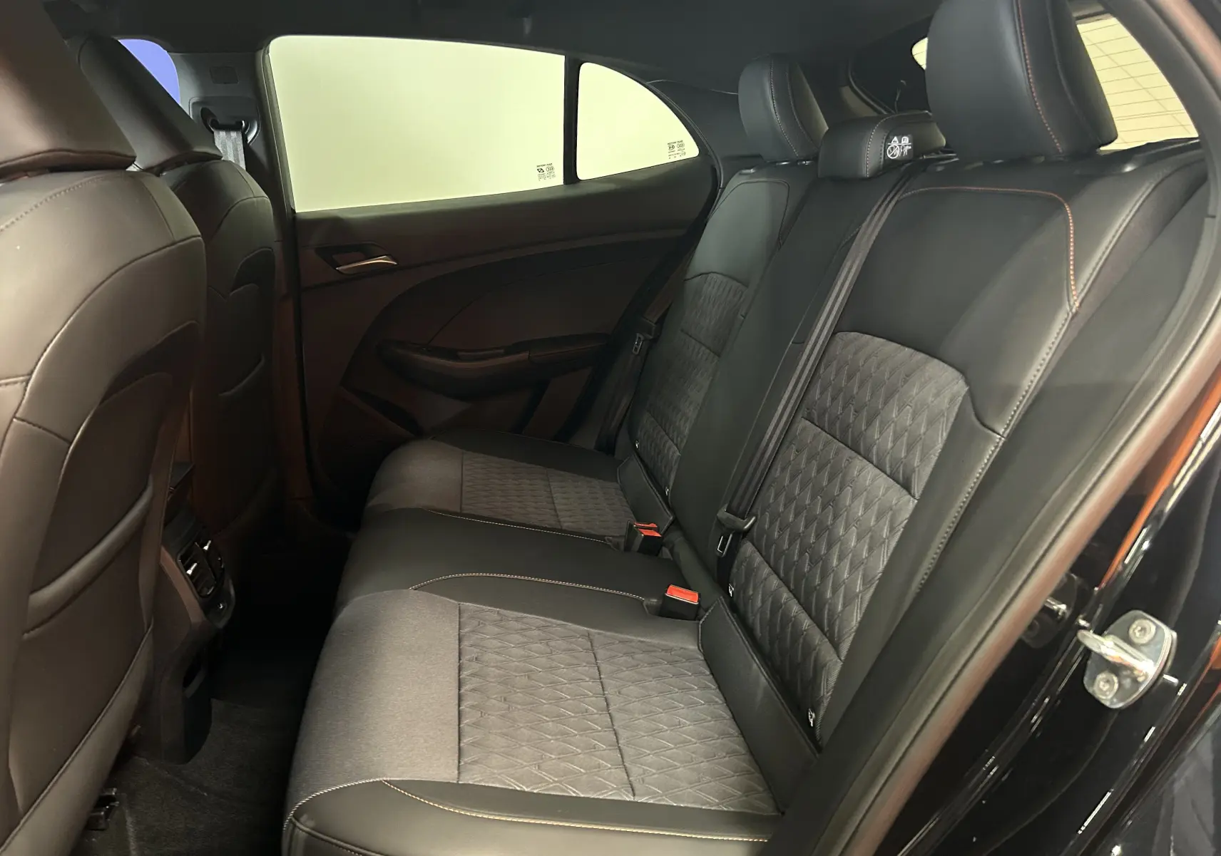 Vue intérieure côté droit des sièges arrière en cuir noir avec surpiqûres orange du MG3 Hybrid+ 195 Luxury 2026 Pebble Black.
