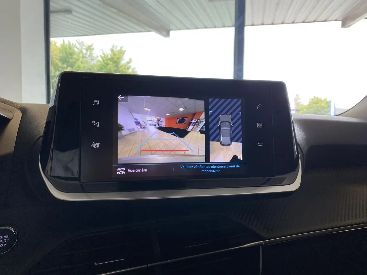 Écran tactile intérieur du Peugeot 2008 e-136 Allure Pack montrant la caméra de recul et l'aide au stationnement.