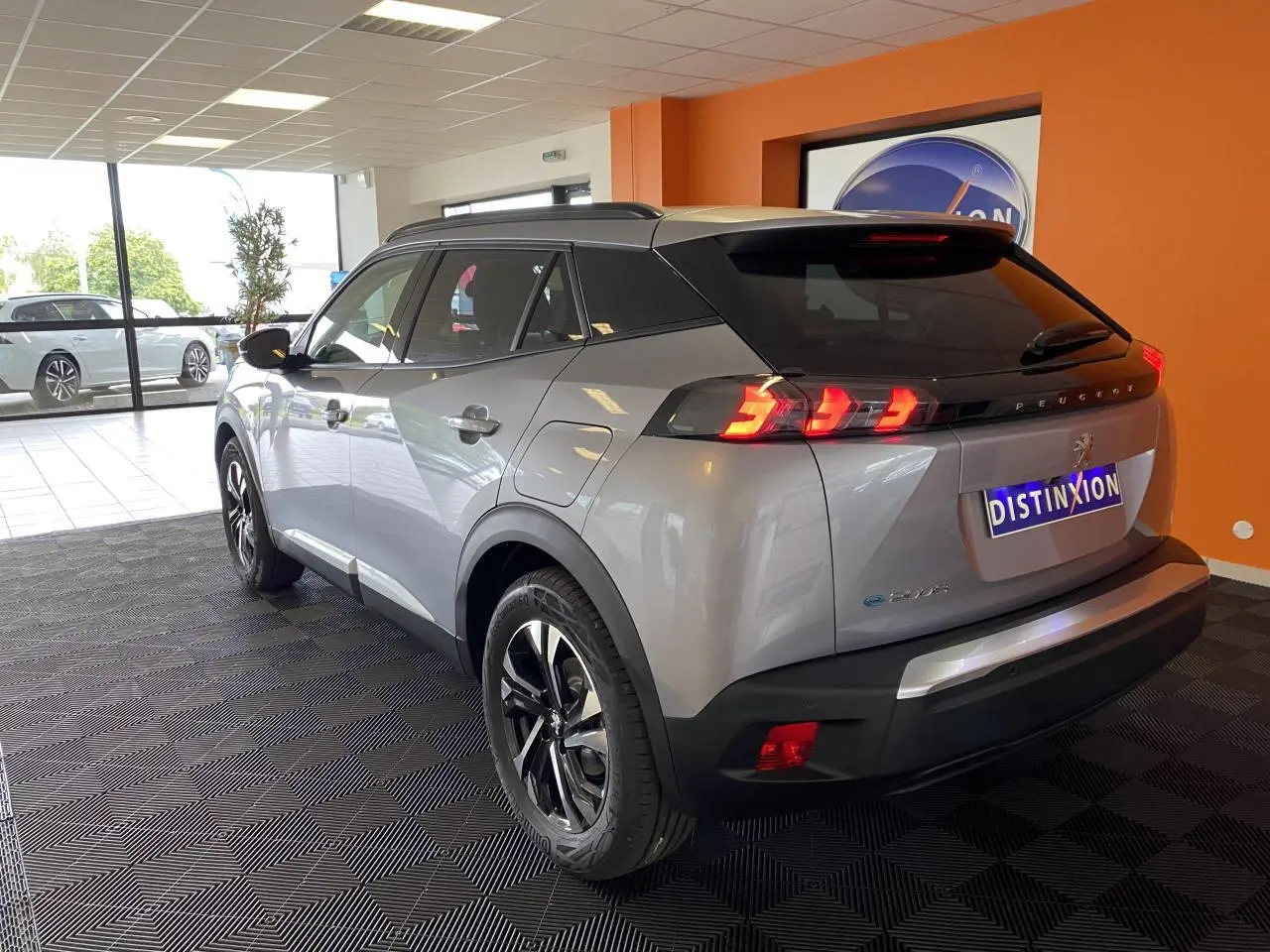 Vue 3/4 arrière droite d'un Peugeot 2008 e-136 Allure Pack gris Artense avec jantes alliage 17'' en showroom.