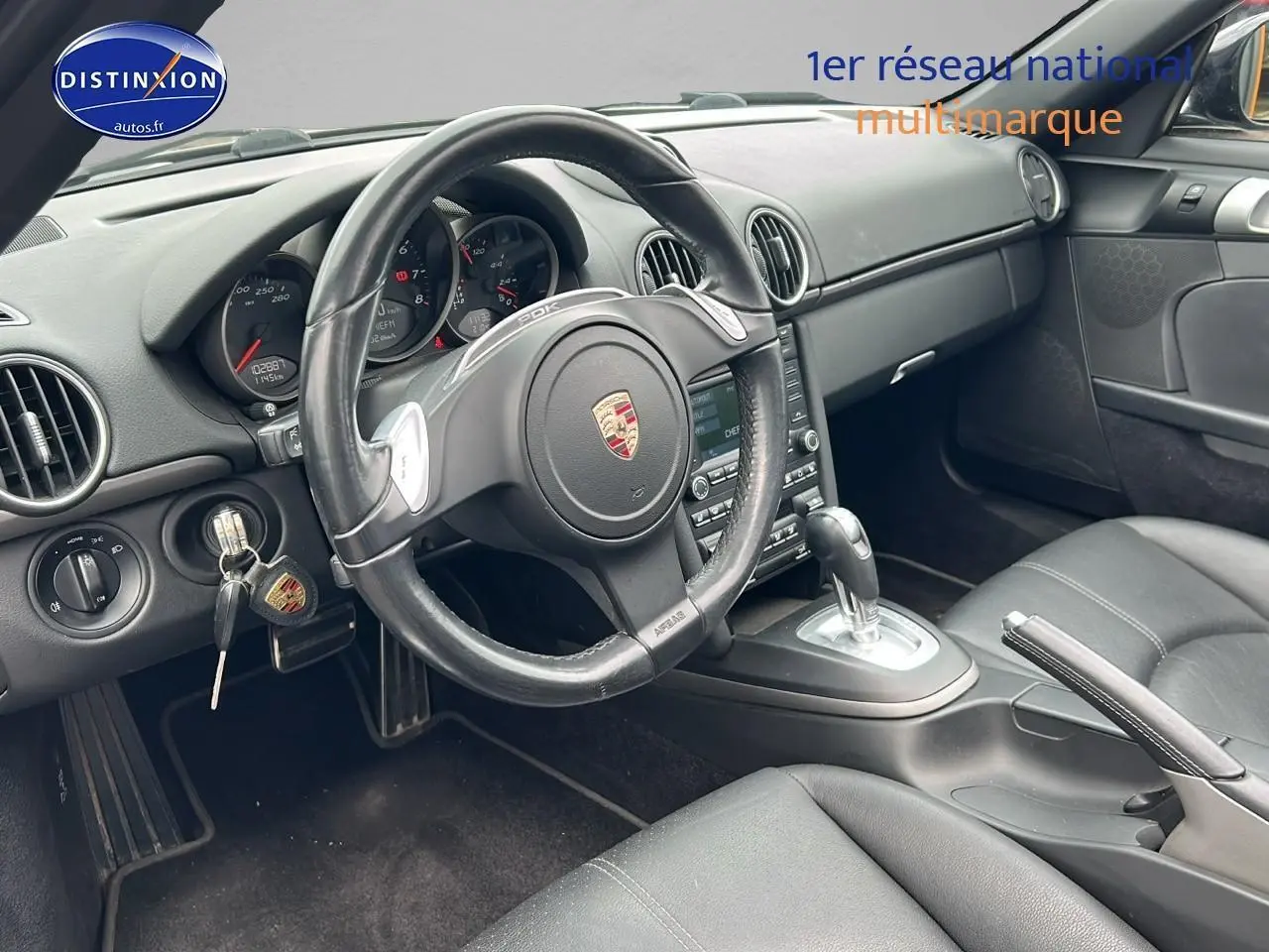 Intérieur noir de la Porsche Boxster 987 vue côté conducteur, volant cuir avec palettes et tableau de bord complet.