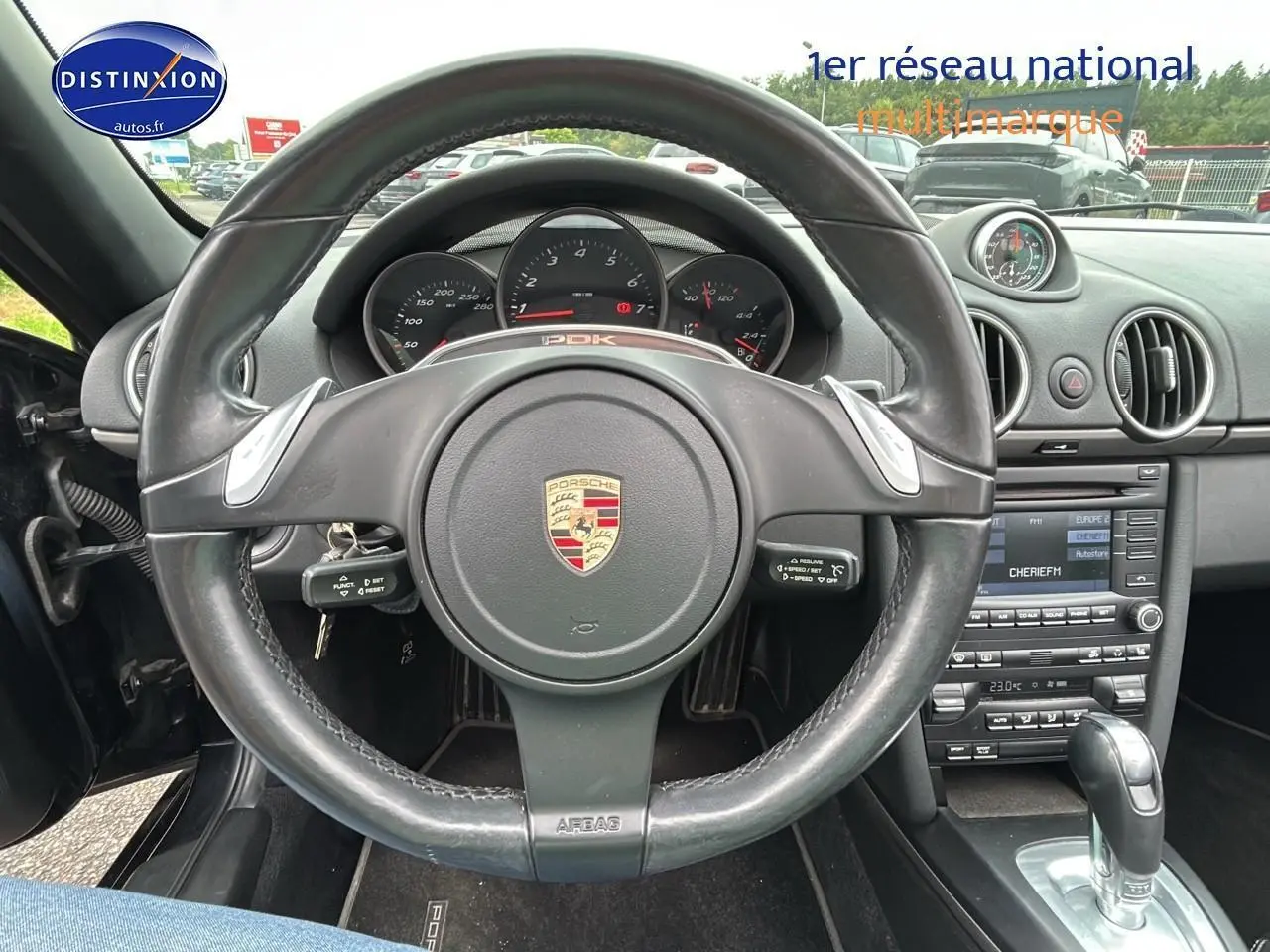 Vue rapprochée du volant cuir noir et du tableau de bord de la Porsche Boxster 987 2.9 PDK de 2012.