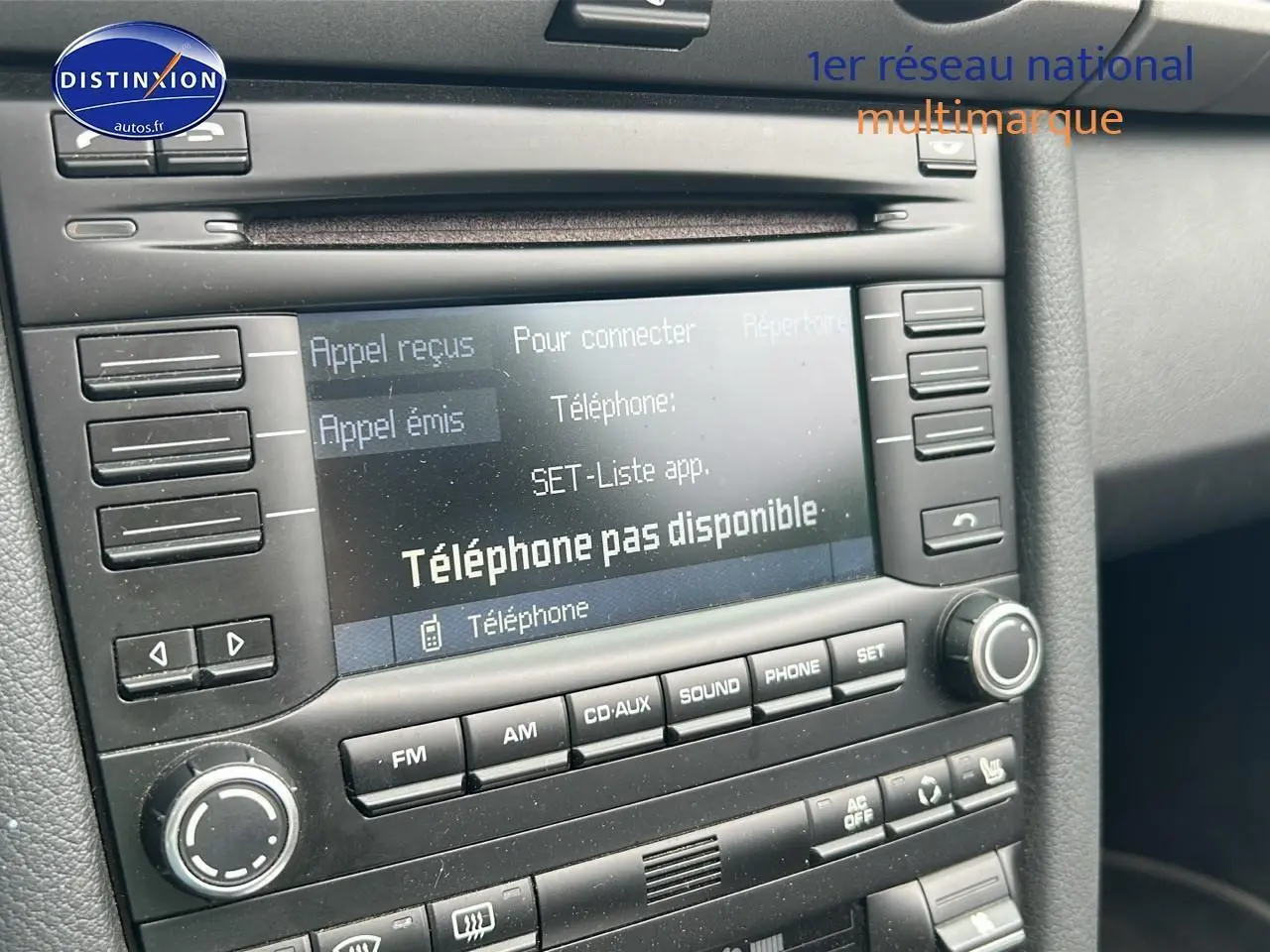 Gros plan sur l'écran multimédia et la console centrale noire d'une Porsche Boxster 987 2.9 PDK de 2012.