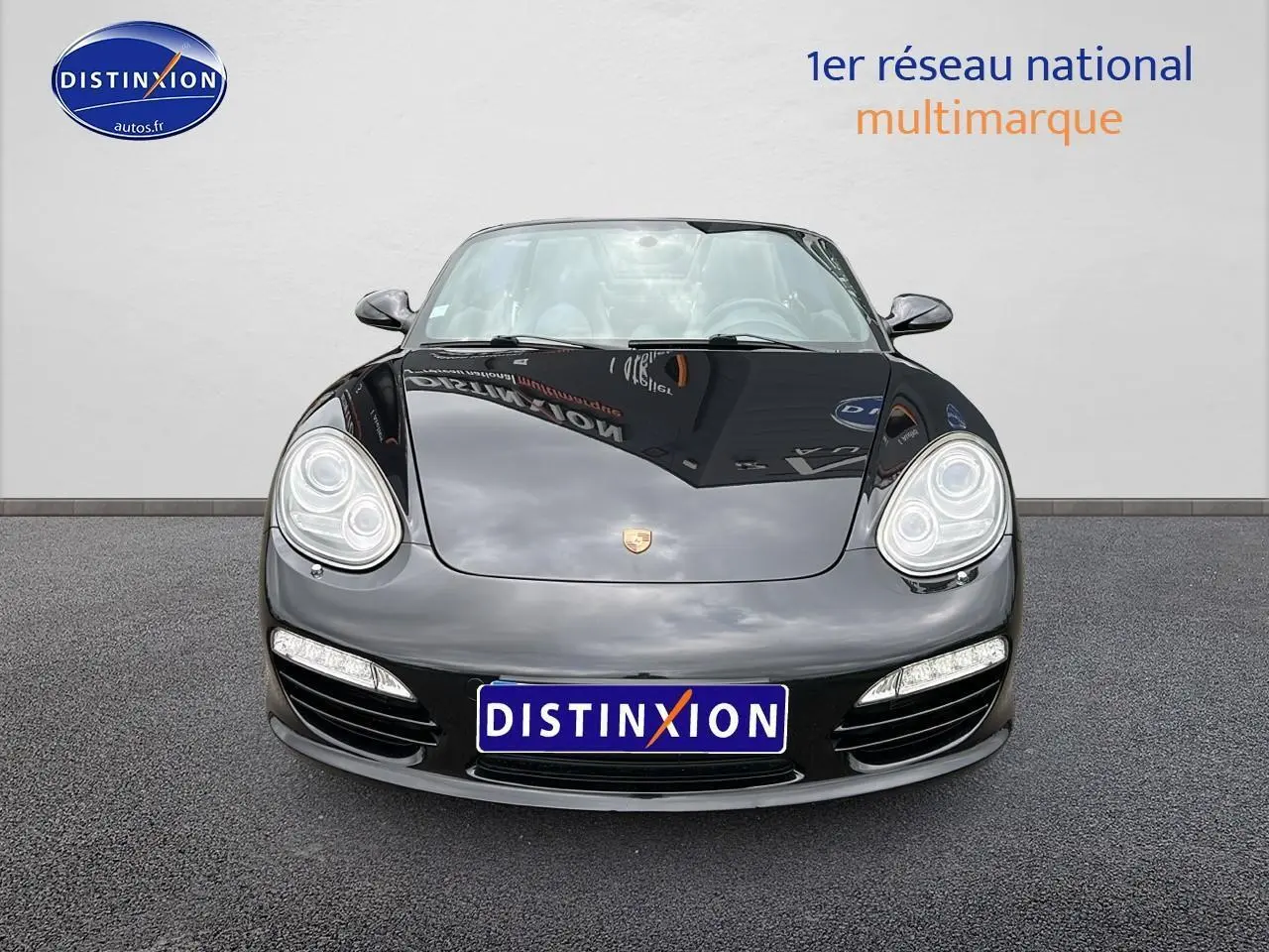 Vue frontale d'une Porsche Boxster 987 noire avec phares bi-xénon et feux LED, sur fond neutre.