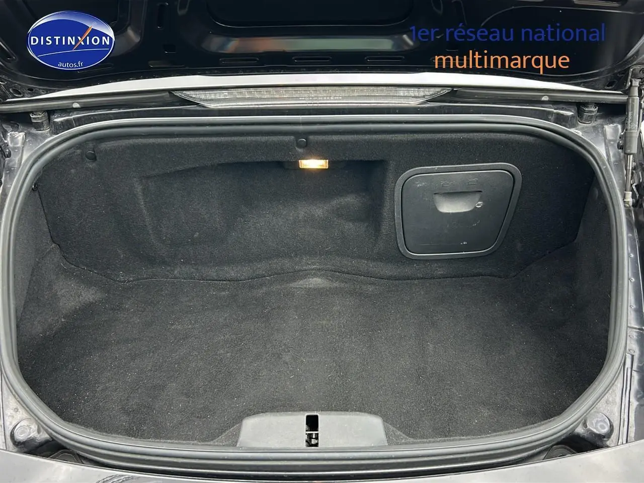 Coffre arrière ouvert d'une Porsche Boxster 987 noir, montrant l'espace de rangement intérieur et la lumière intégrée.