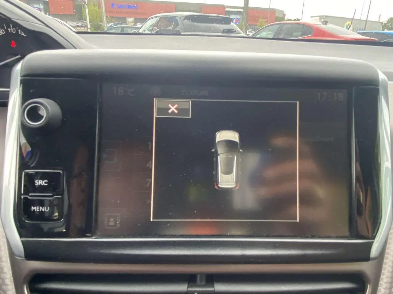 Écran tactile central du tableau de bord du Peugeot 2008 blanc de 2015, affichant la vue de dessus du véhicule en stationnement.