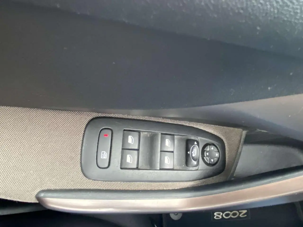 Commande des vitres électriques et rétroviseurs sur la portière côté gauche d'un Peugeot 2008 blanc de 2015.